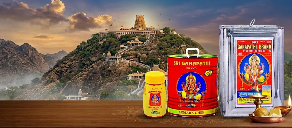 Sri Ganapathi brand pure ghee tins and jars placed against a scenic mountain temple background.